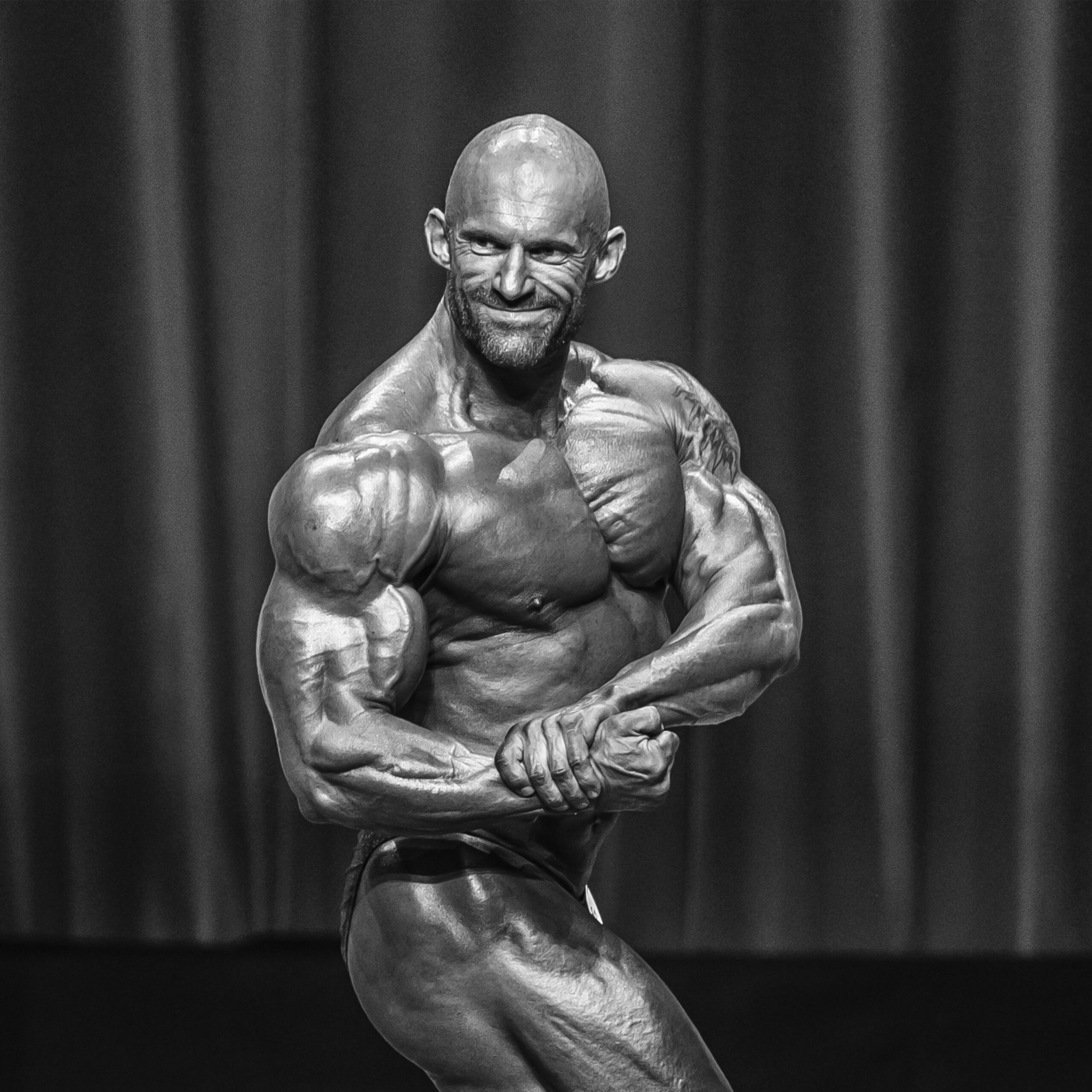 Bodybuilder Marco Bachmann, posiert auf der Bühne, zeigt Muskeln und Kraft.