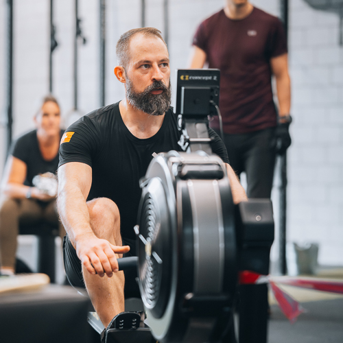 Mann trainiert auf Rudergerät im Fitnessstudio während intensiver Cardio-Workout-Session